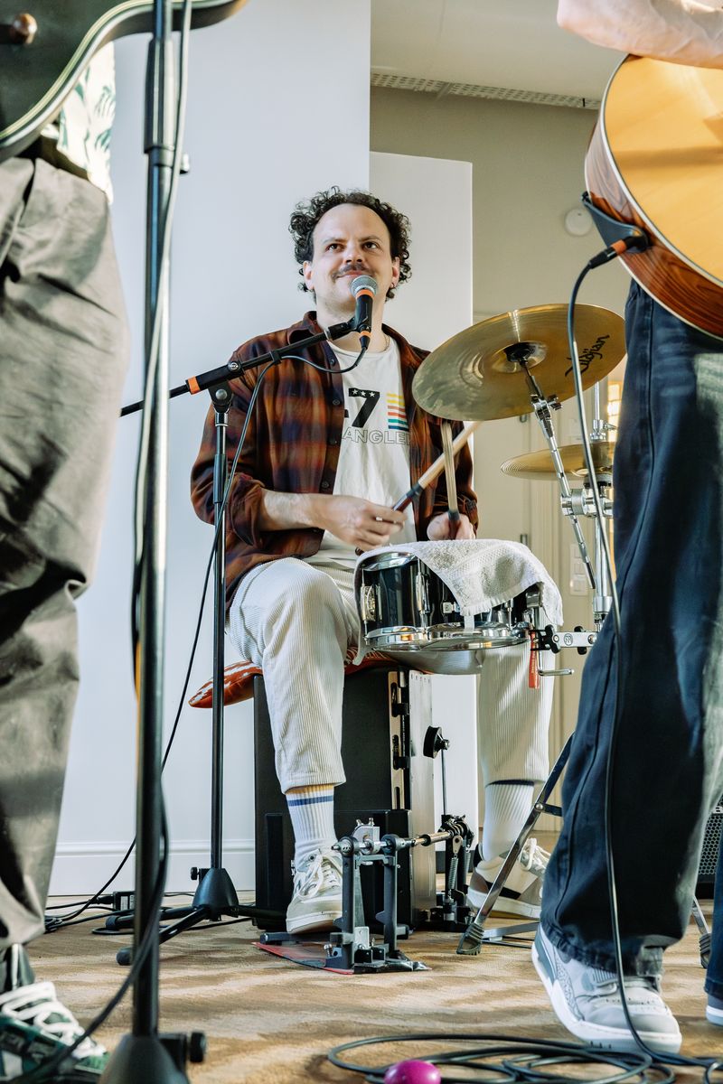 Simon Potet en concert, assis sur un cajon avec une caisse claire, entouré de deux guitaristes